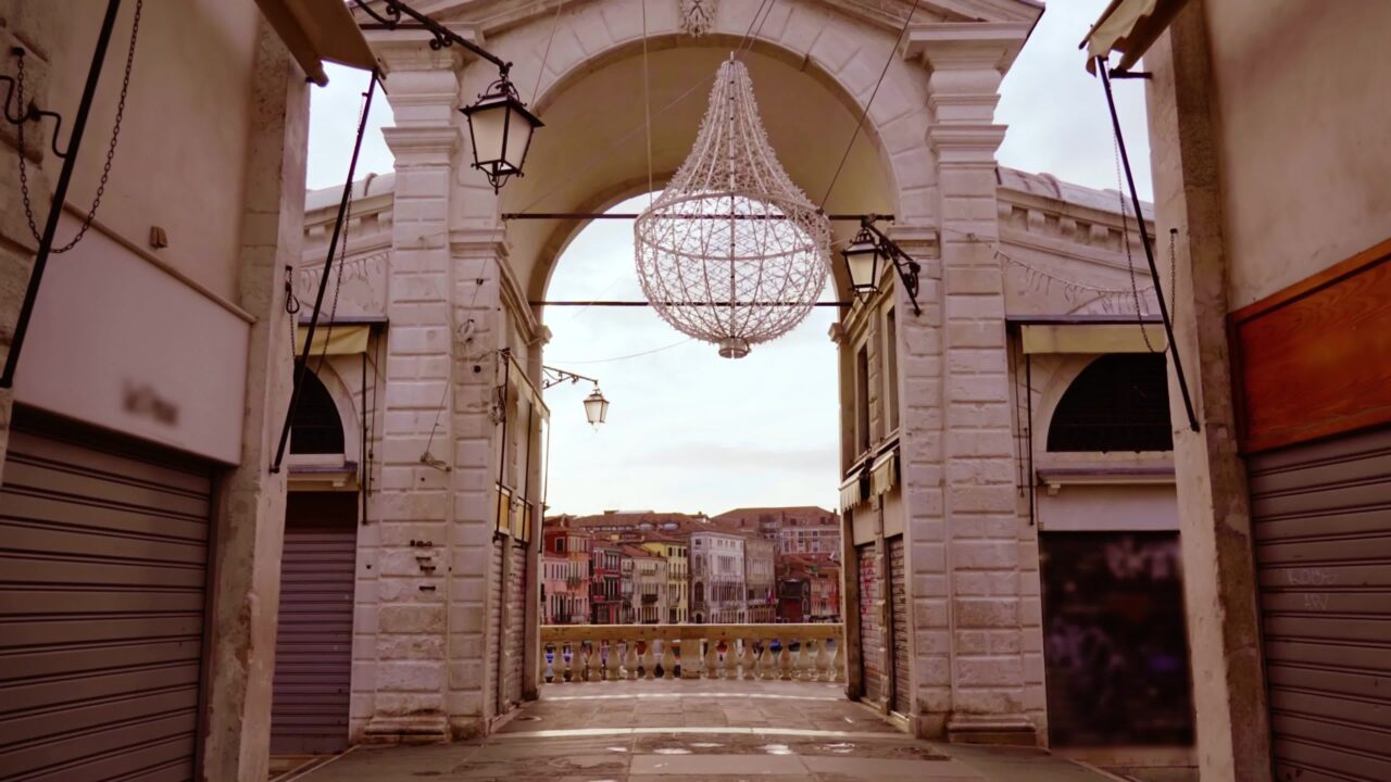 Arco in pietra sul ponte di Rialto sul Canal Grande con piccole gondole