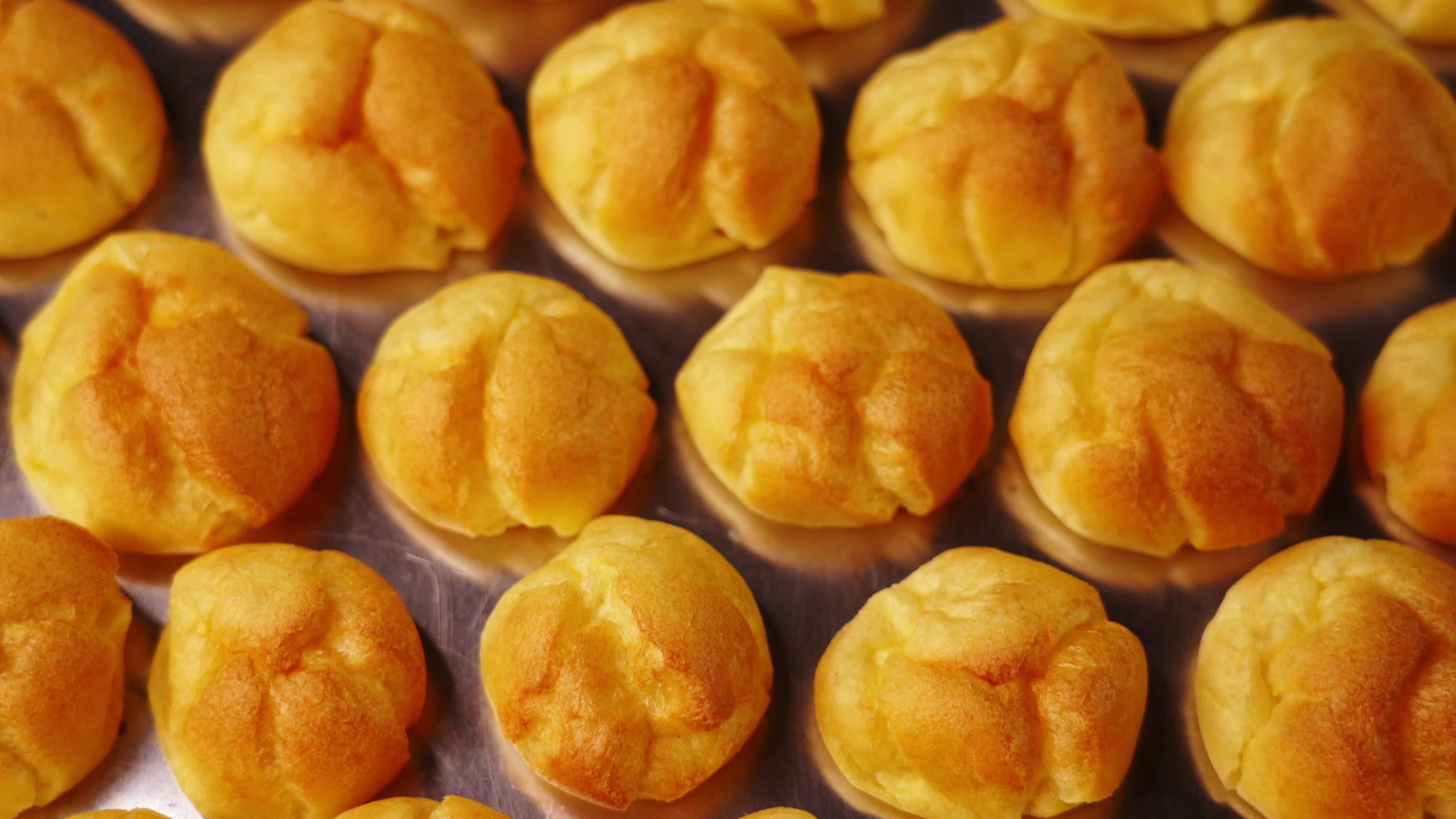 Freshly made cream puffs on baking sheet