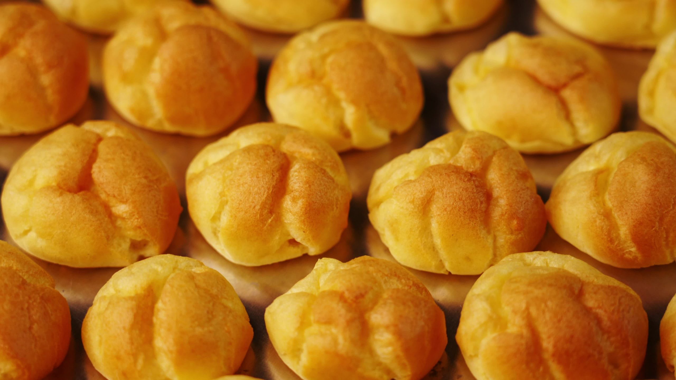 Motion over delicious fresh eclair buns on shiny baking tray