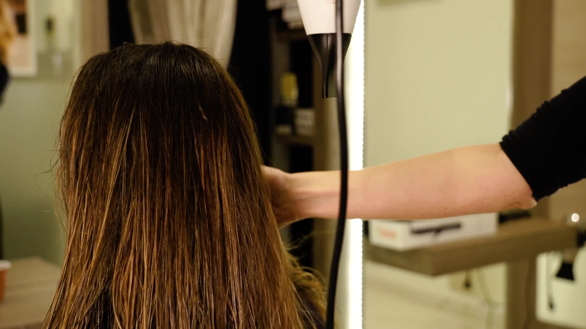 The hairdresser dries the hair with a hair dryer