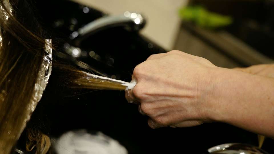 Hair of the lady at the hairdresser is covered with white gel