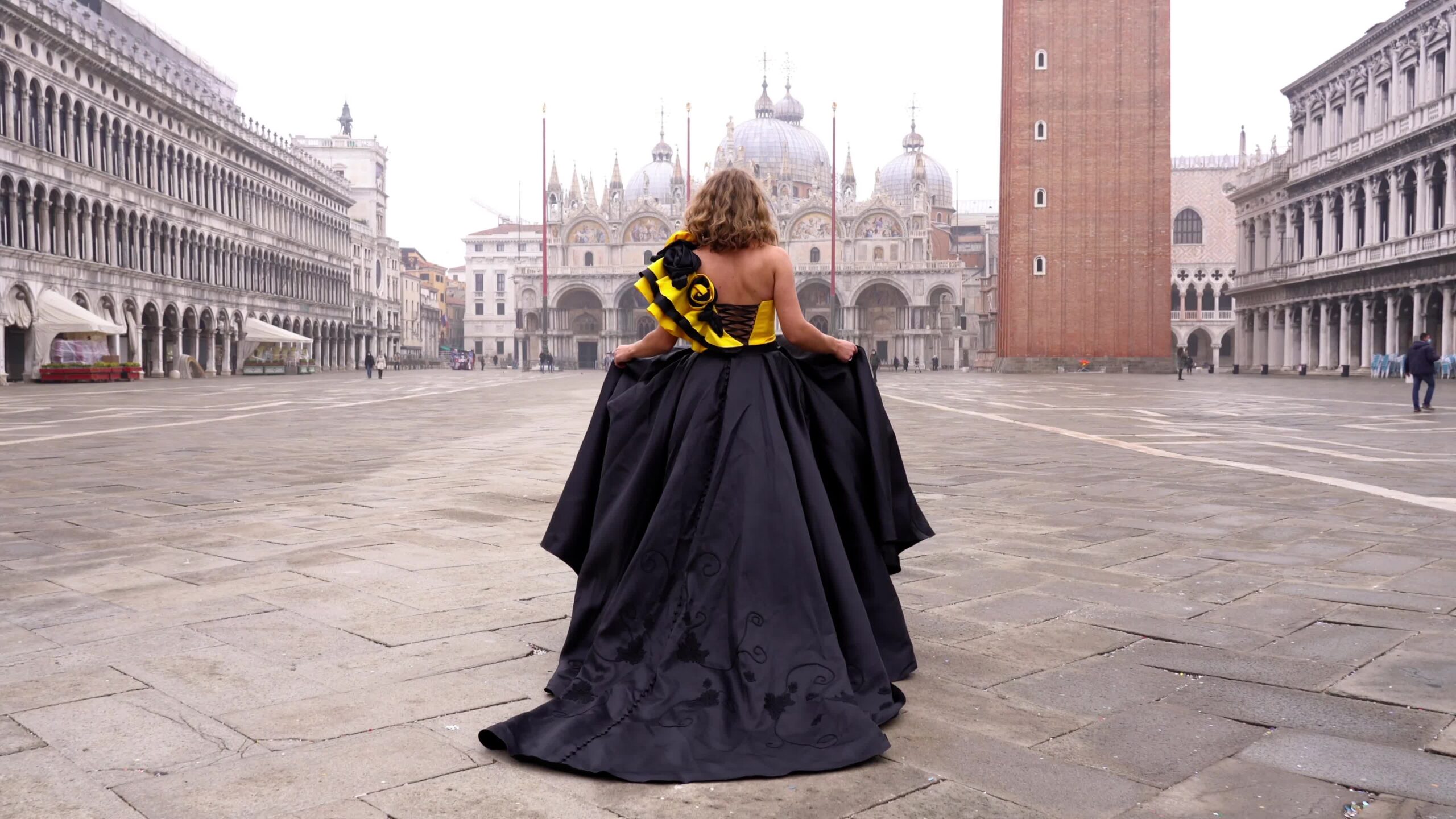 Woman in dress with flounce and long train walks on square