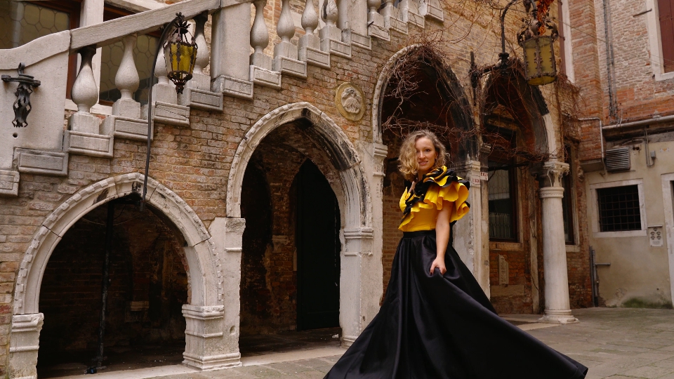 Model in carnival dress walks along empty italian courtyard