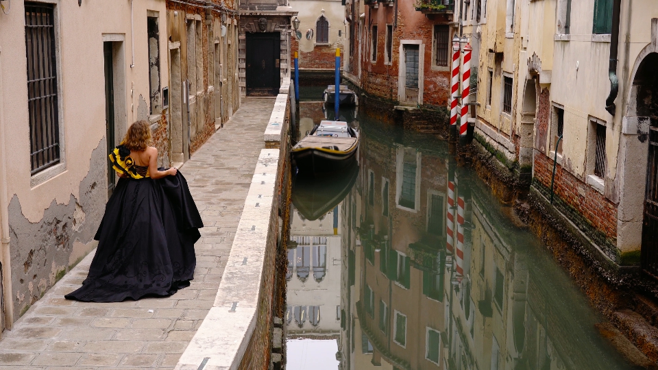 Model in evening dress walks along venice channel sidewalk