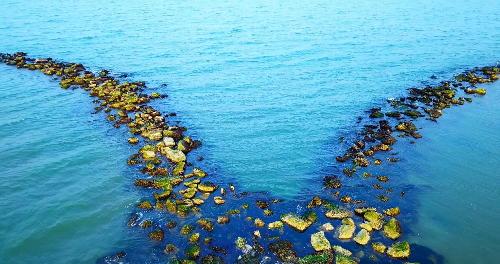 Il frangiflutti di roccia artificiale si spacca contro il mare blu infinito