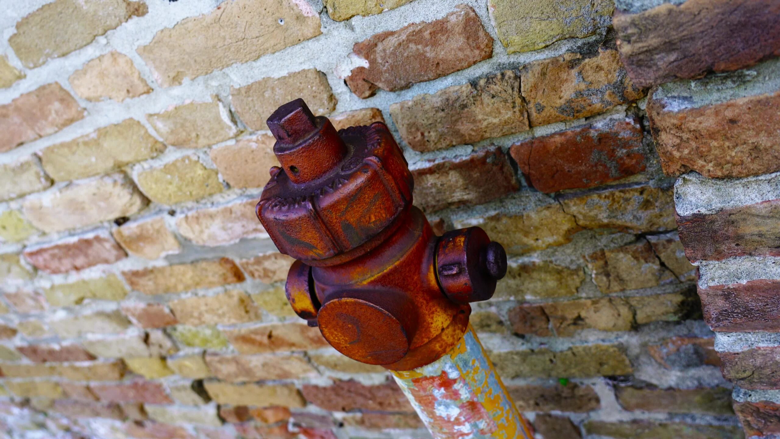 Outdated fire hydrant with red rusty top and greyish support