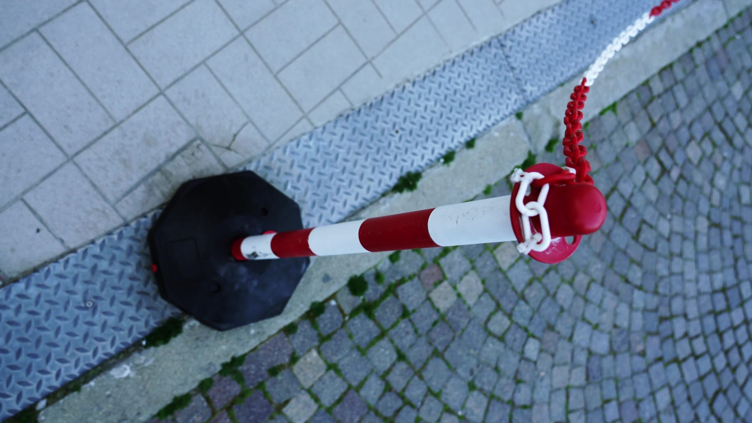 Red and white pole with coloured chain located on drain