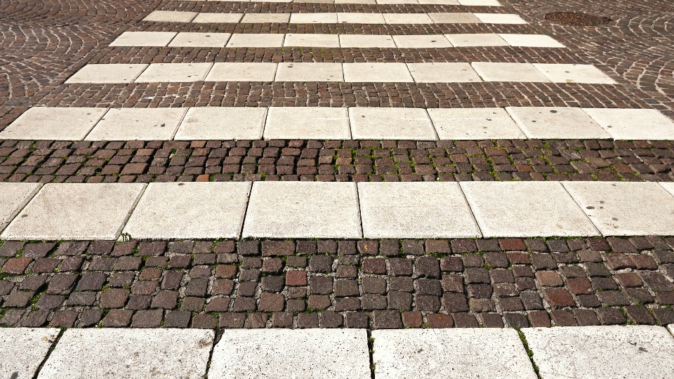 White crosswalk tiled with large white stones on paved road