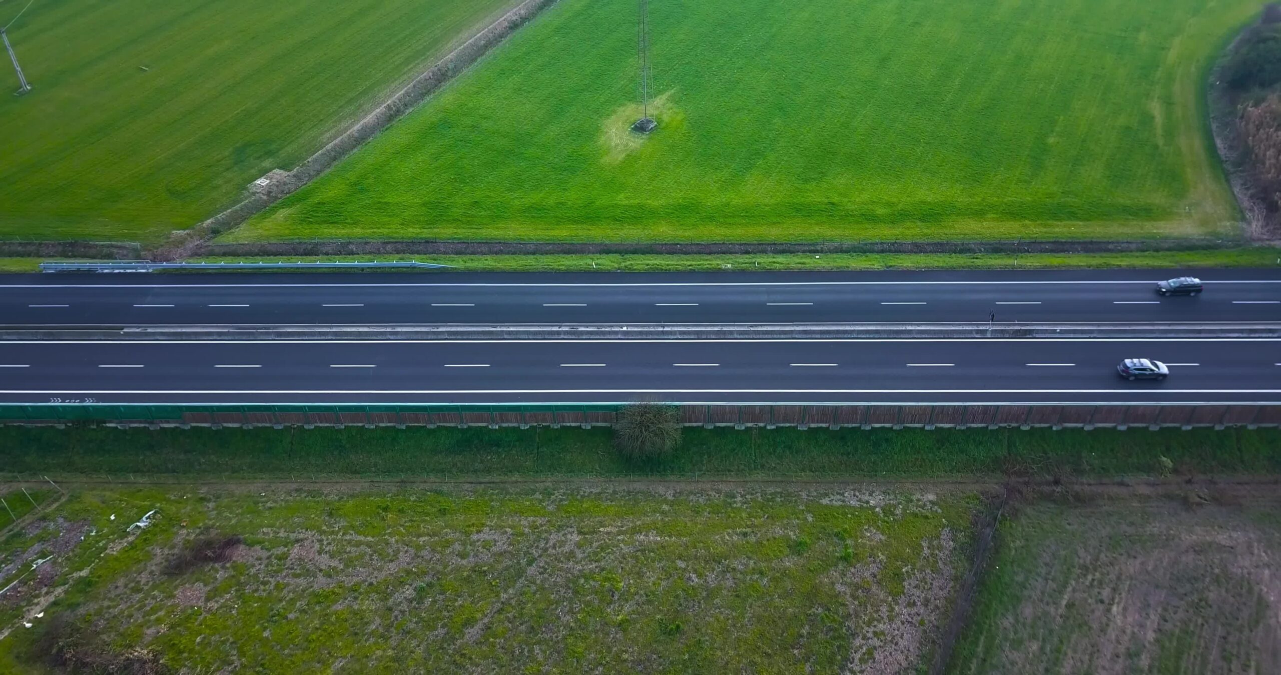 Le auto percorrono un’autostrada asfaltata divisa tra i campi in erba