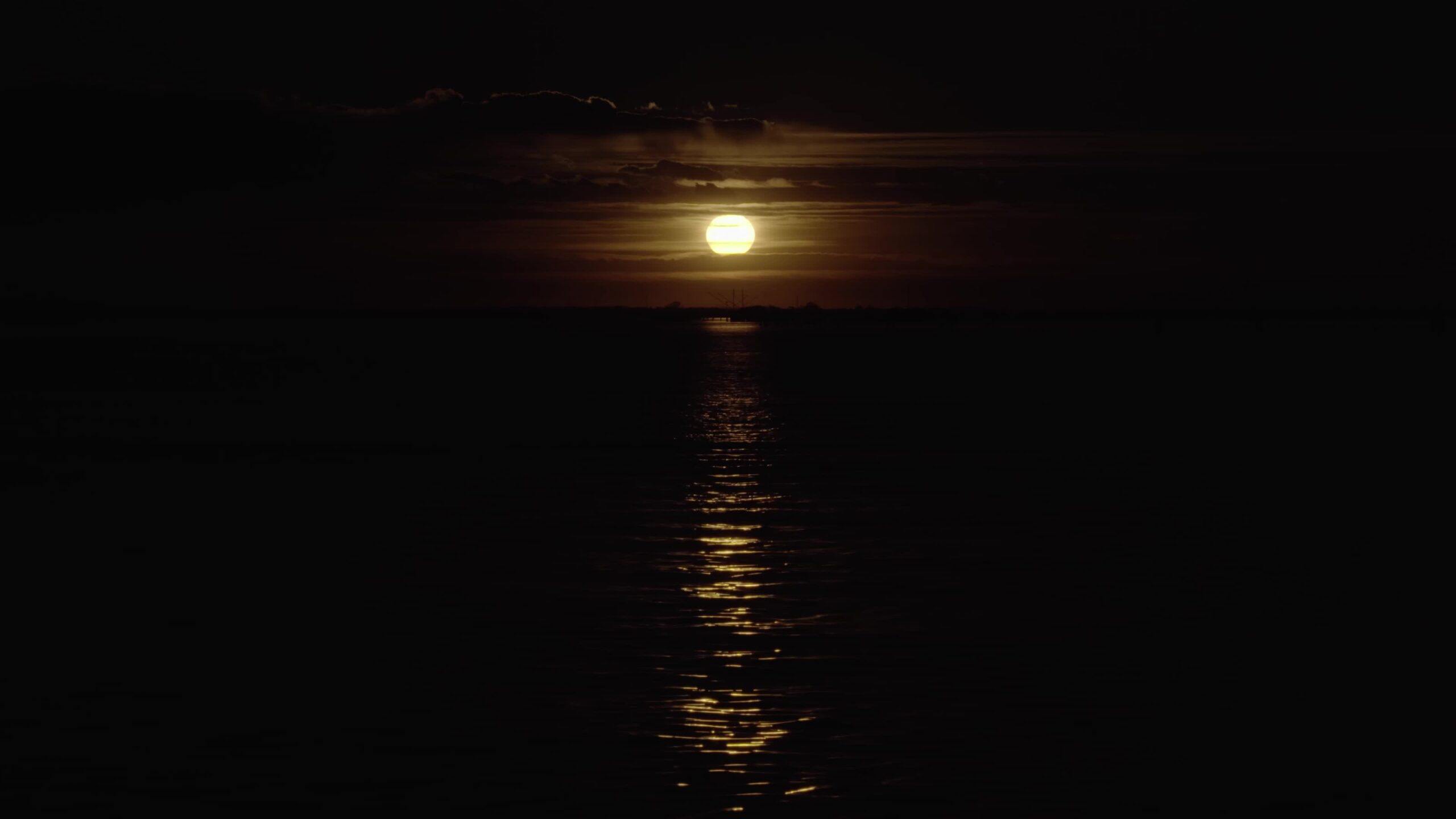 Lunar disk light reflects on water creating path in sea