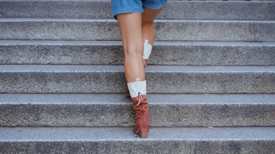 Lady tourist goes up stairs into medieval building portico