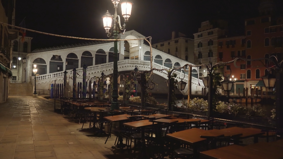 Folded cafe tables against famous Rialto bridge at night