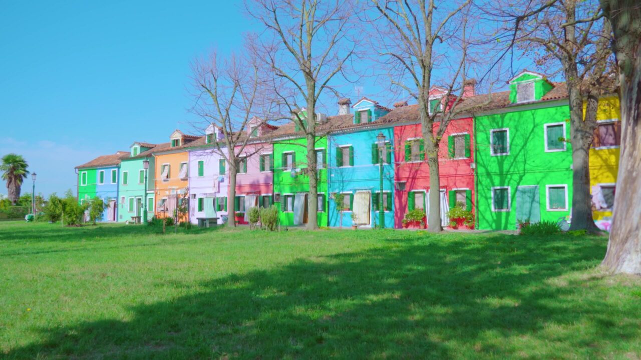 Multicolored semi-detached houses stand near green meadow