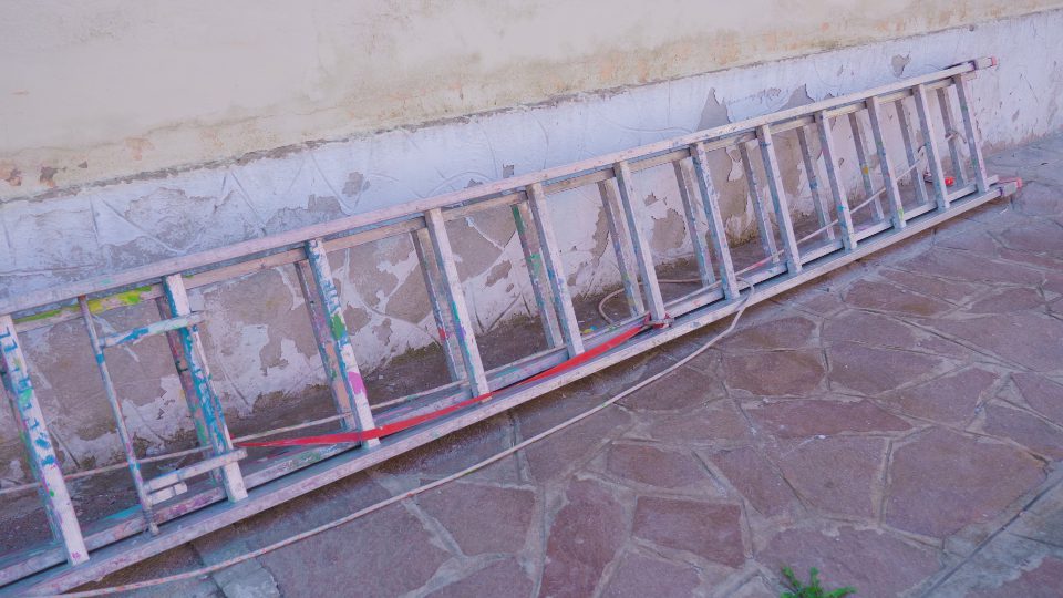 Old stepladder lies on ground leaned on building wall