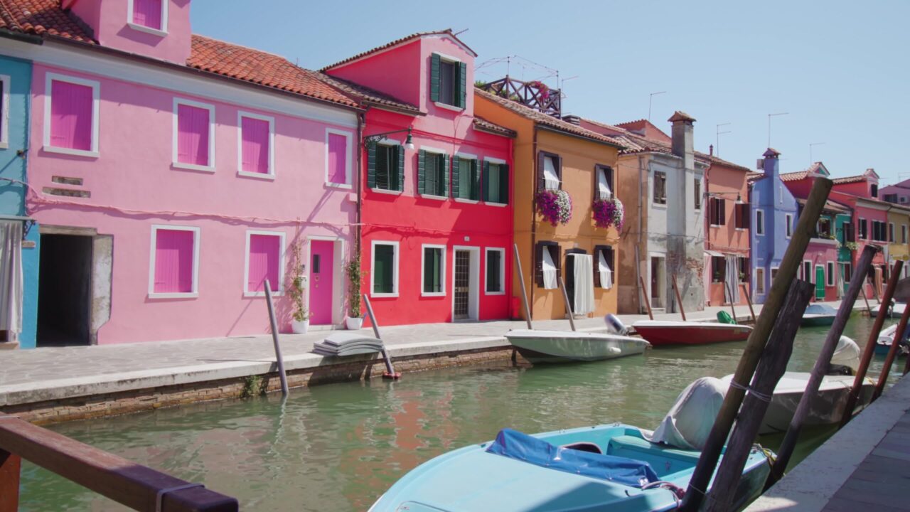 Colorful houses on Burano water channel bank with boats