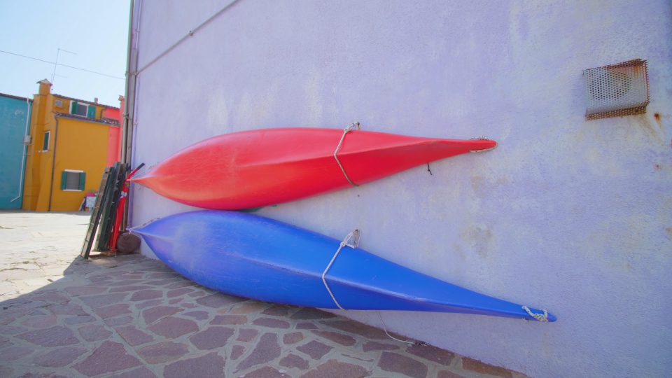 Canoe boats fixed leaning against wall of house in Burano