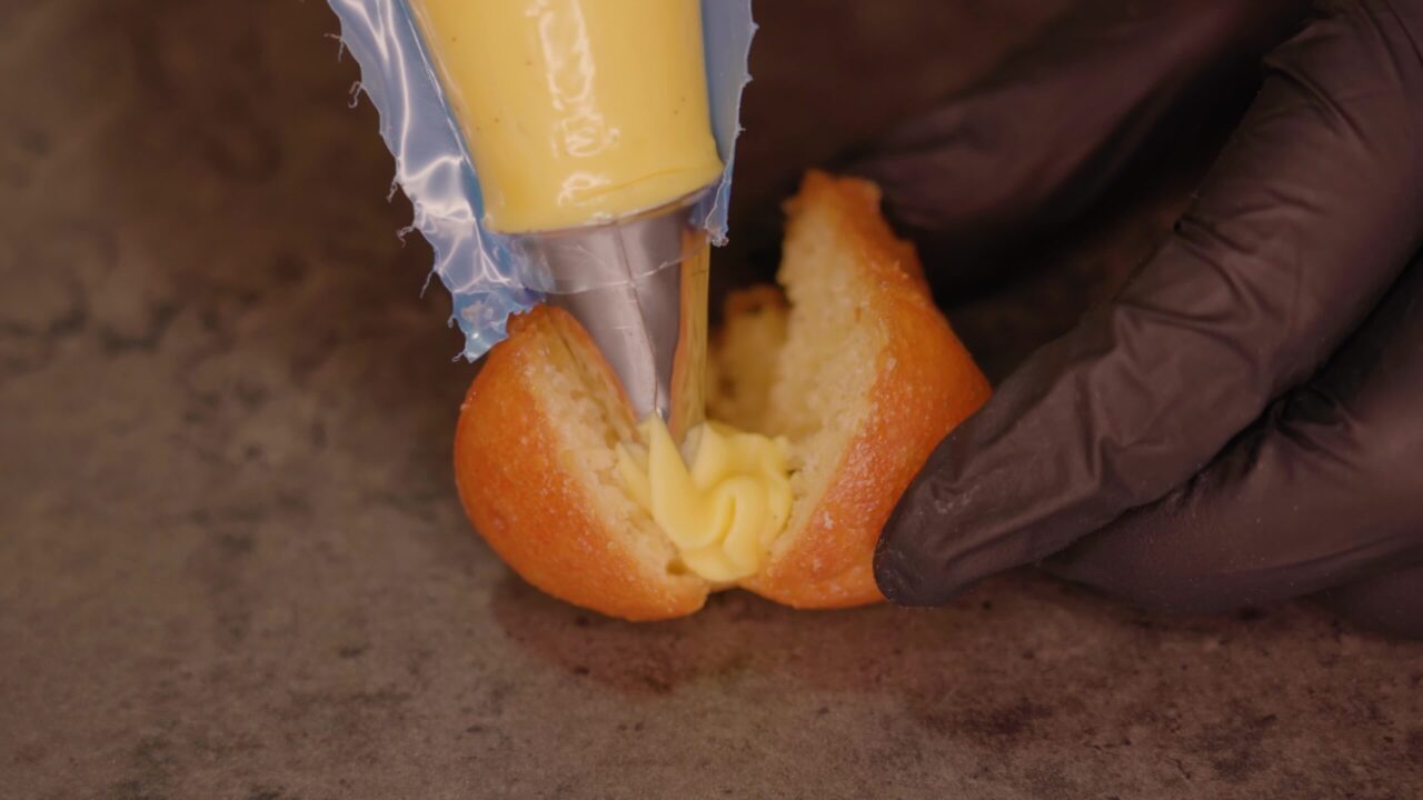 Confectioner applies custard on cake with cream injector