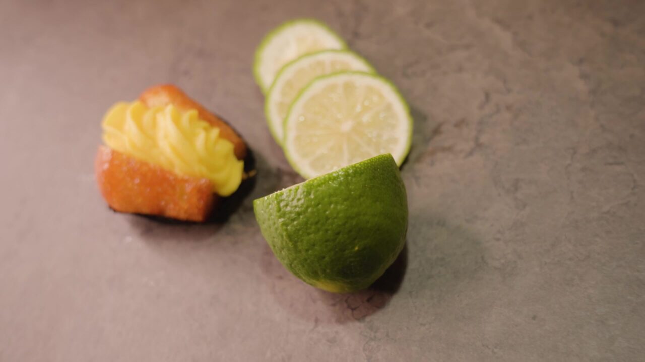 Fresh cupcake with custard and sliced lime lie on table