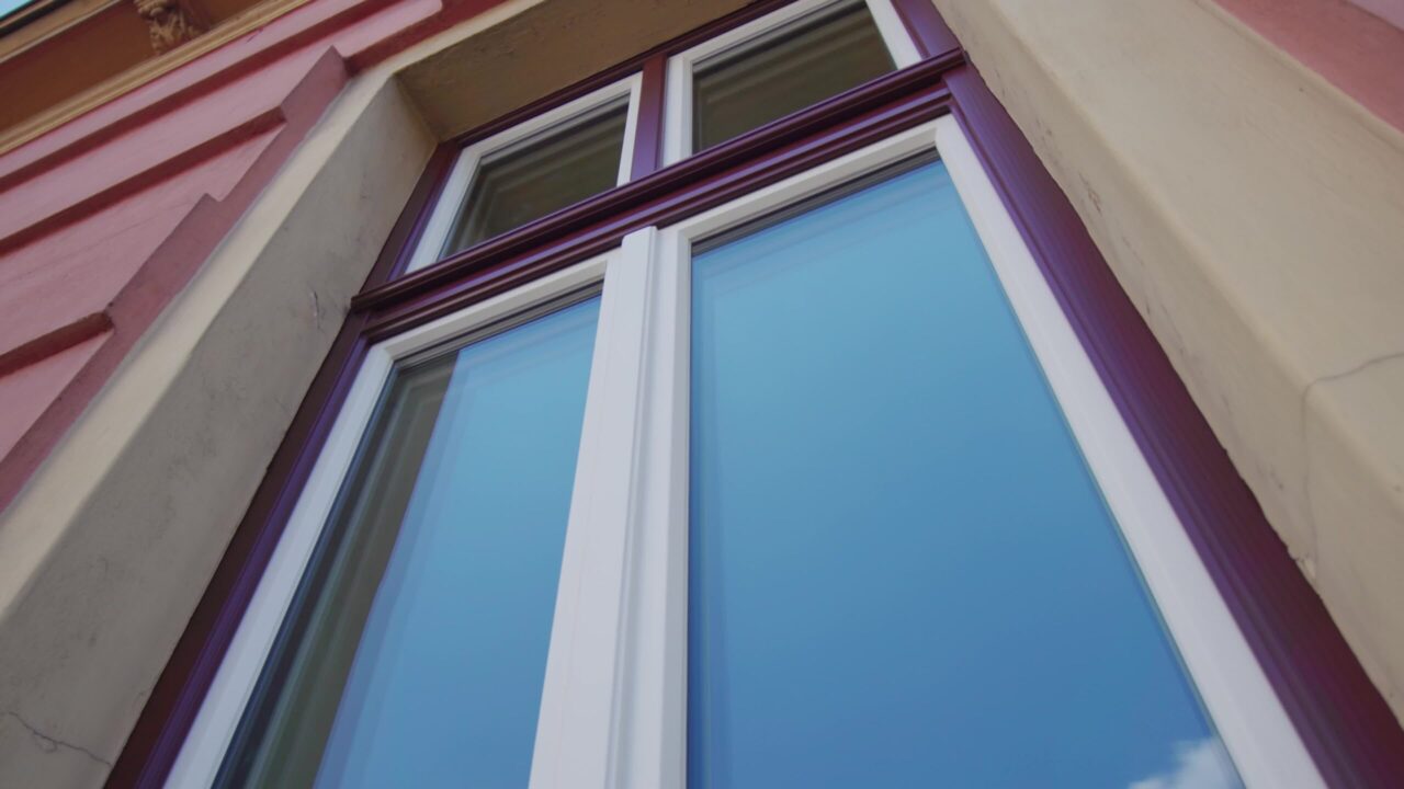 Glass of purple frame window reflects blue sky in Ljubljana