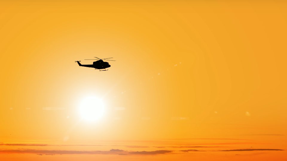 Dark silhouette of helicopter flies against bright sun