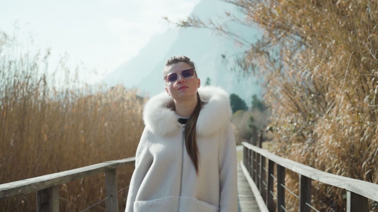 La donna alla moda con gli occhiali cammina sul ponte di legno in riserva