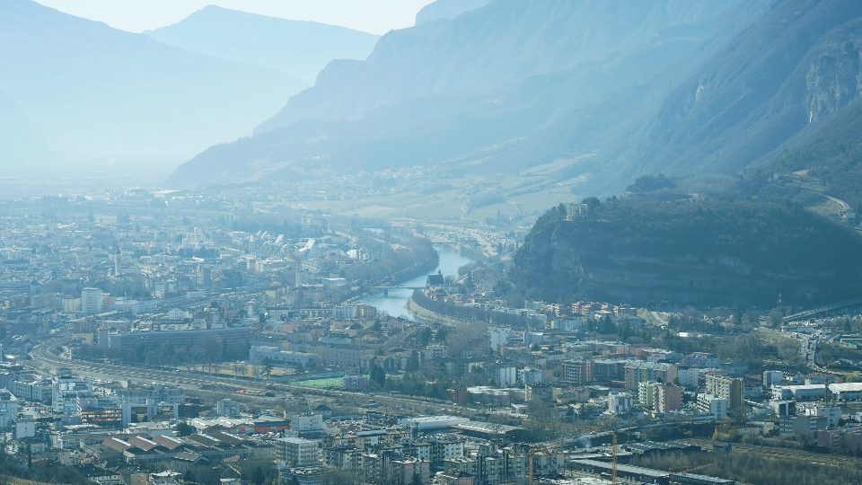 Città di Trento con piccoli edifici e fiume davanti le montagne