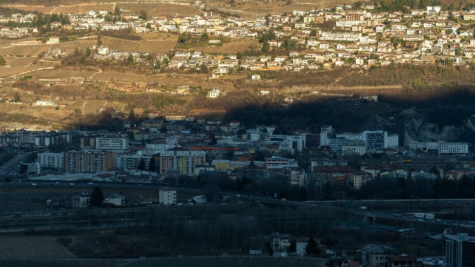 Le auto sulla strada di Trento con gli edifici in ombra