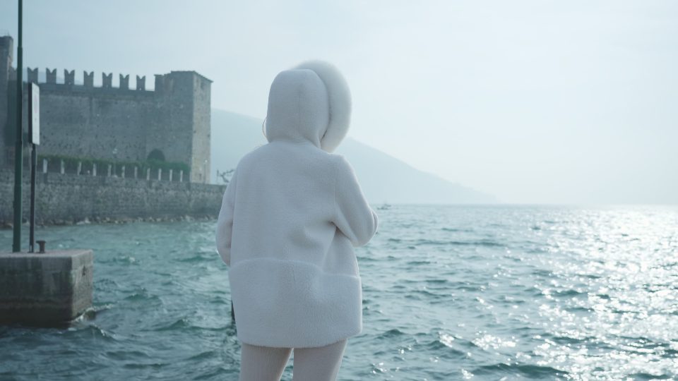 Donna sta guardando il lago di Garda con le onde causate dal vento