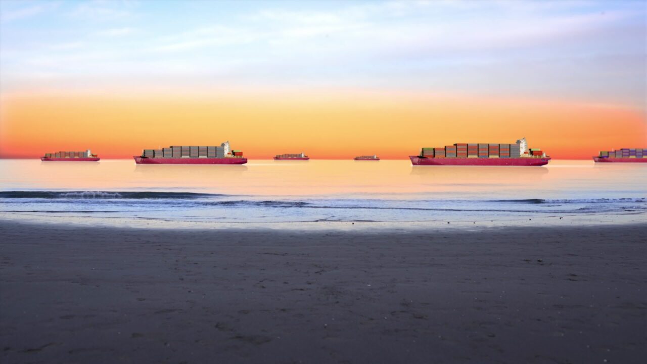 Spiaggia e navi mercantili che trasportano container