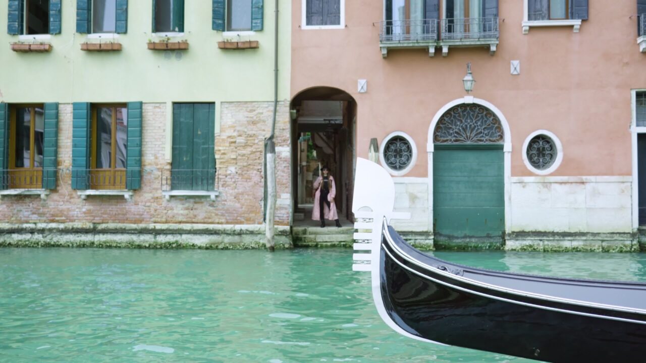 Woman stands on threshold of building near water channel