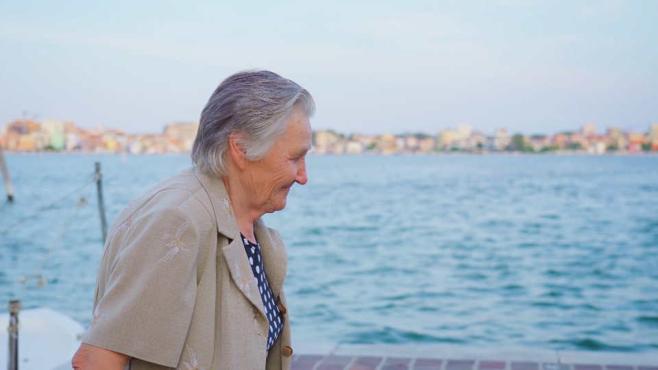 Anziana viaggiatrice cammina sul lungomare di Chioggia sorridente