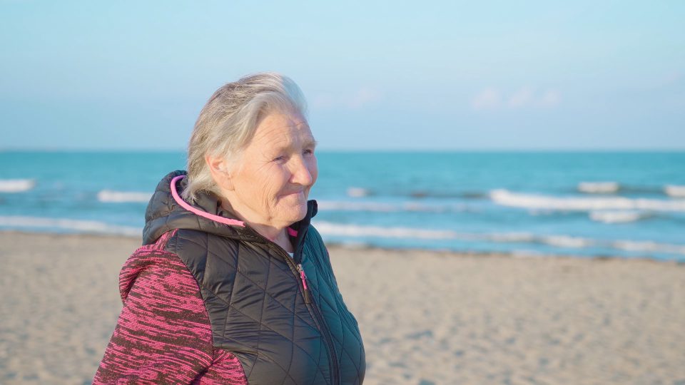Elderly woman on the beach at the sea