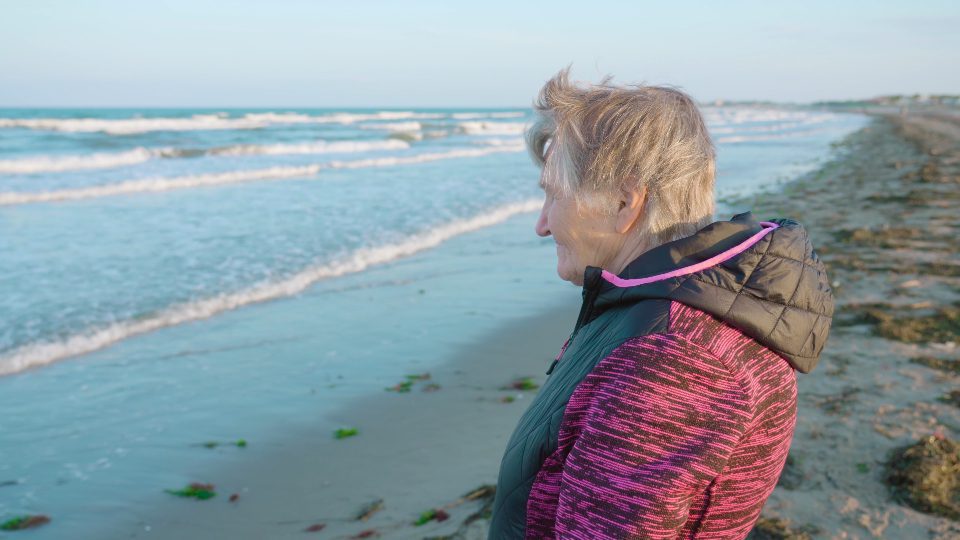 La donna dai capelli grigi gode di una pittoresca vista sul mare dalla costa