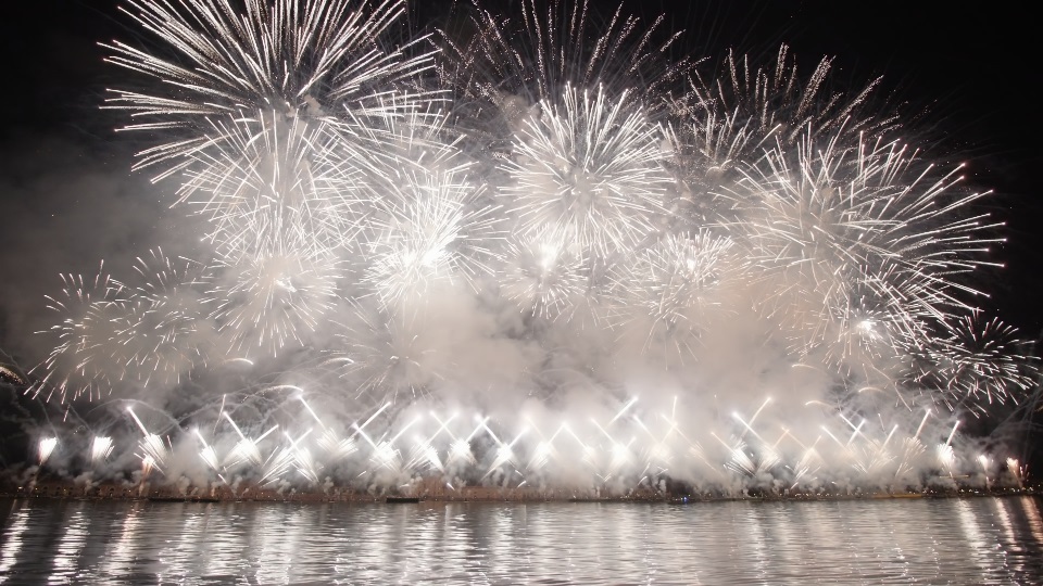 White fireworks burst in air spreading smoke over night city