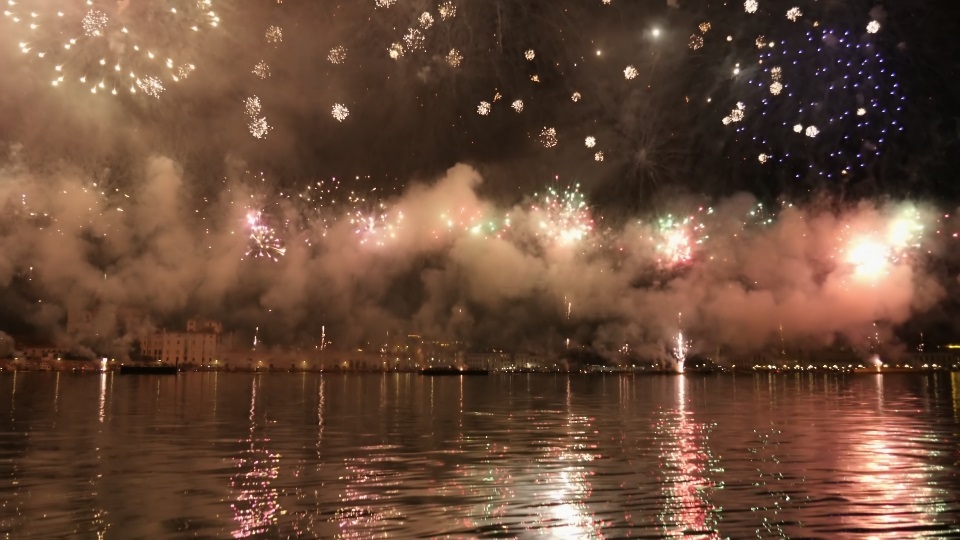 Fuochi d’artificio colorati scoppiano in aria riflettendo sulla superficie dell’acqua