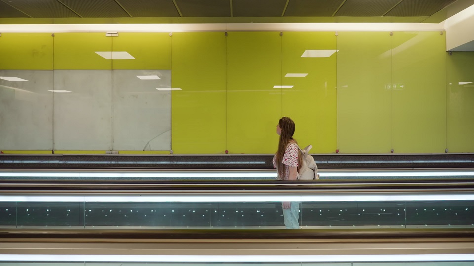 Woman with backpack stands on travellator at train station