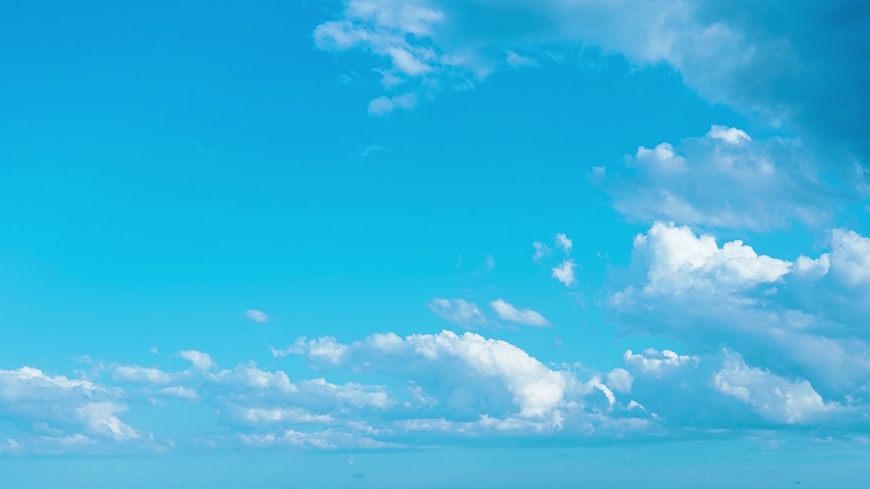 Grey and white cumulus clouds float in clear blue sky