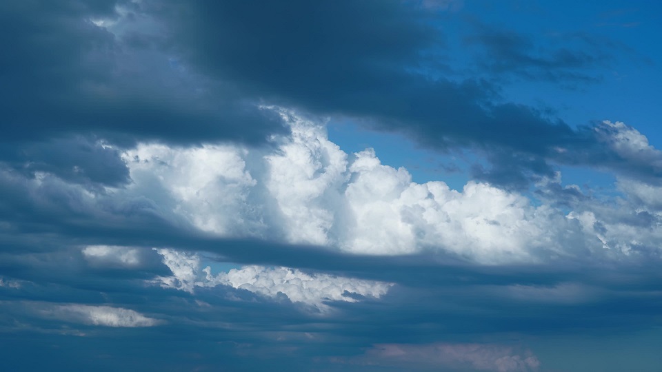 Dark grey and white clouds cover blue sky floating in space