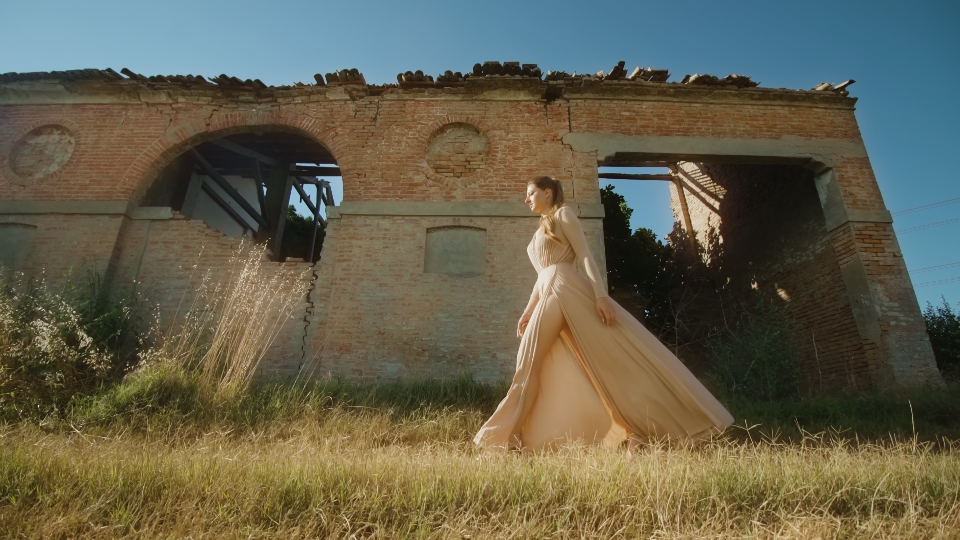 Elegant woman walks in front of broken building