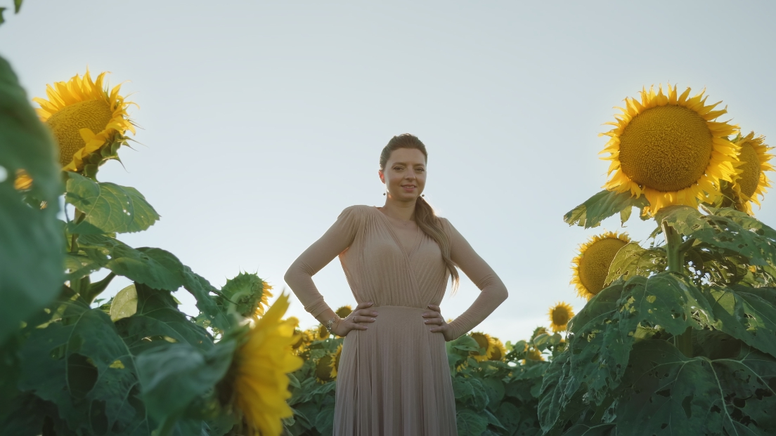 Donna giovane elegante ferma tra girasoli al sole