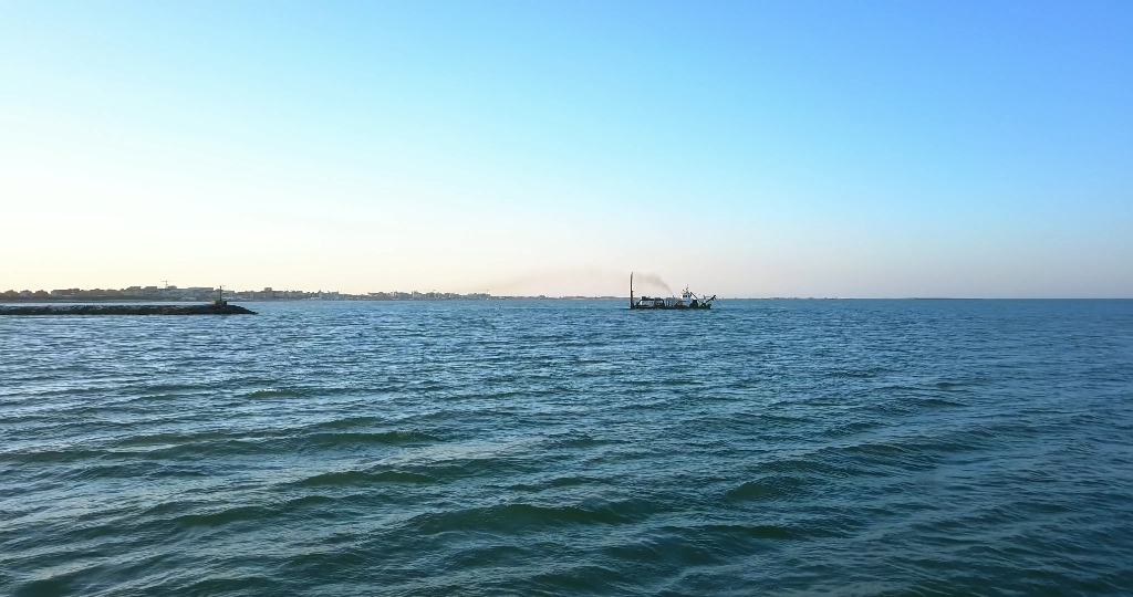 Nave di dragaggio di sabbia sulla riva della spiaggia