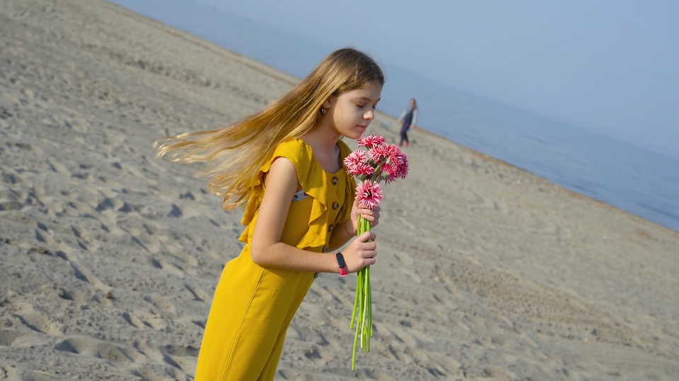 Teenager lifts a bunch of flowers from the sand and throws them on the ground