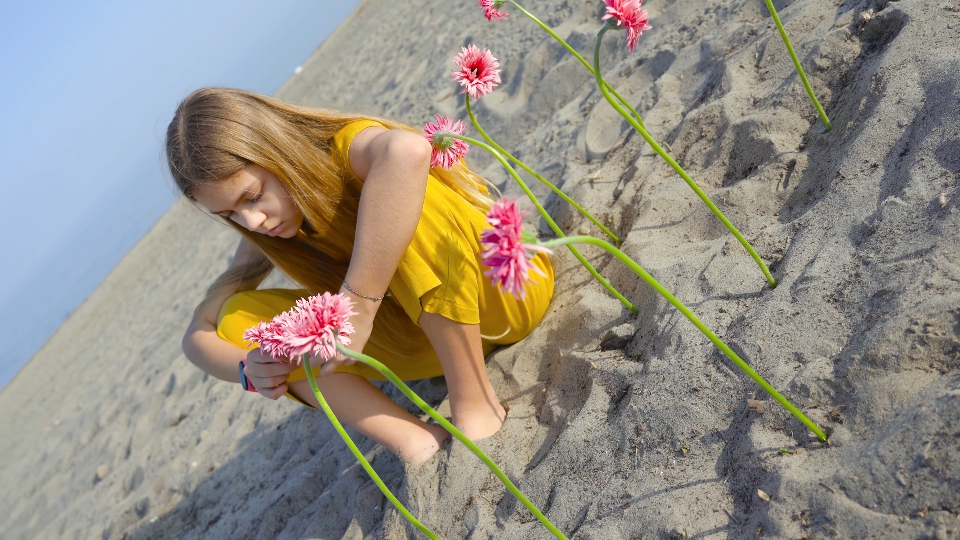 Girl sitting with flowers planted in the sand of the beach