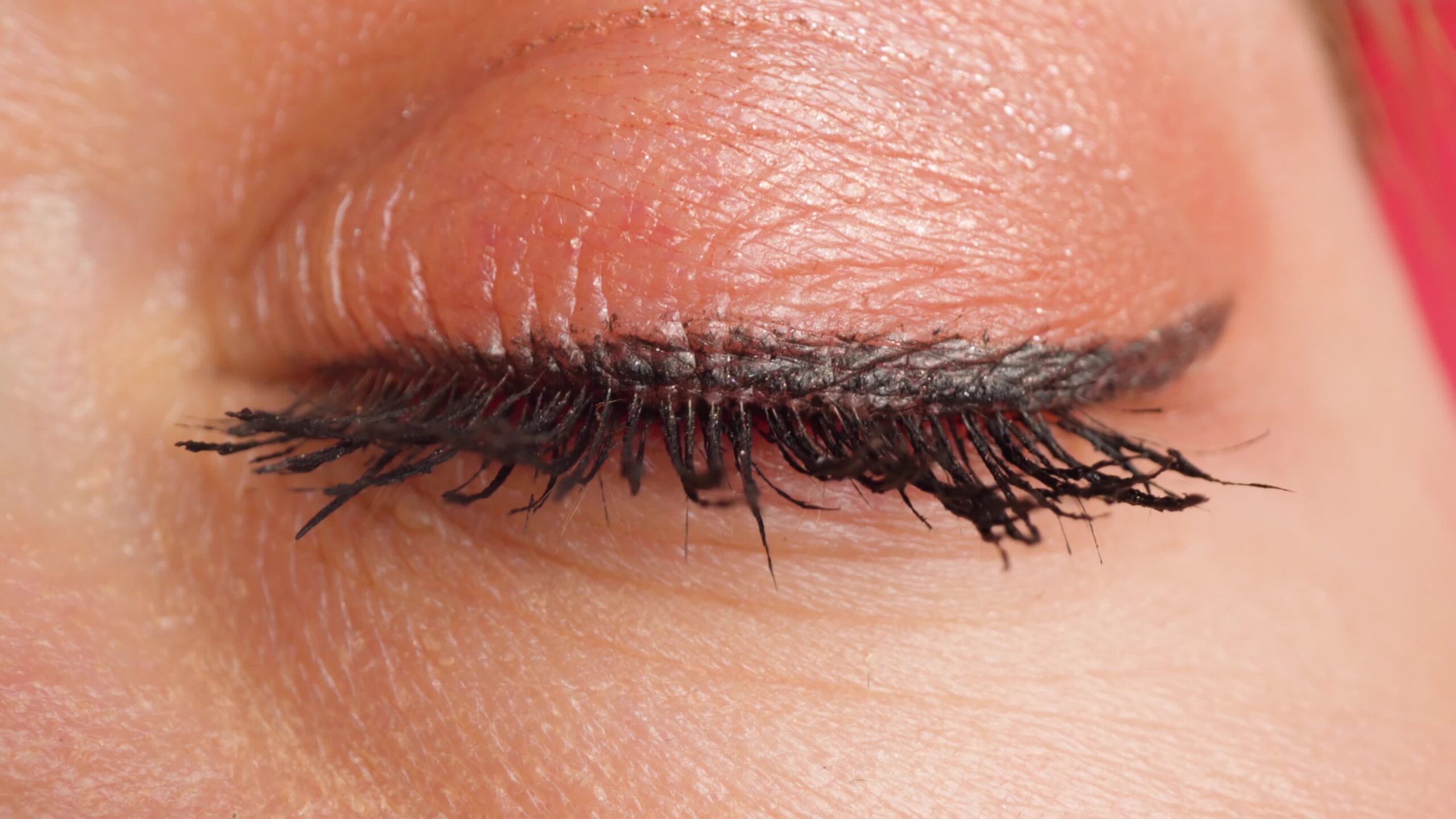 Brown-eyed woman with bright eye makeup blinks macro