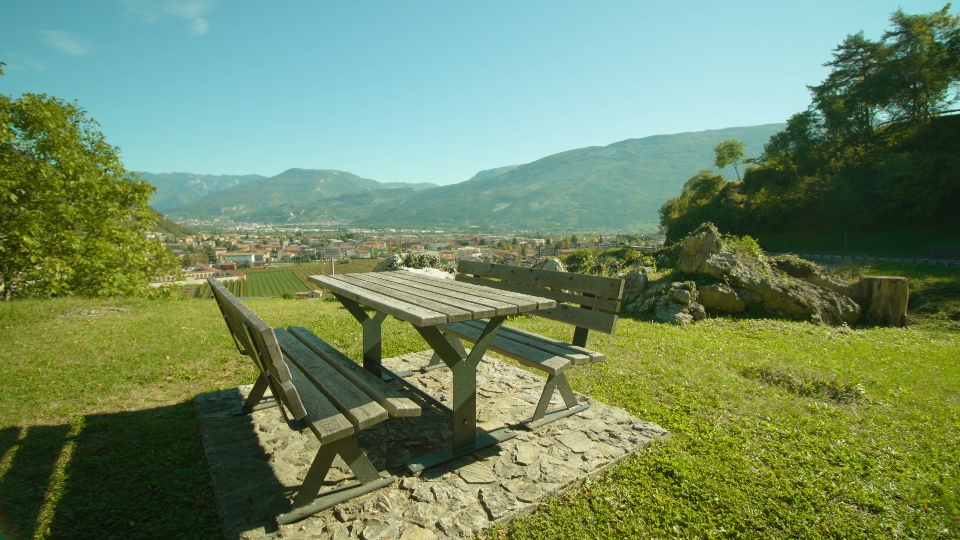 Green meadow with benches with table with Rovereto view