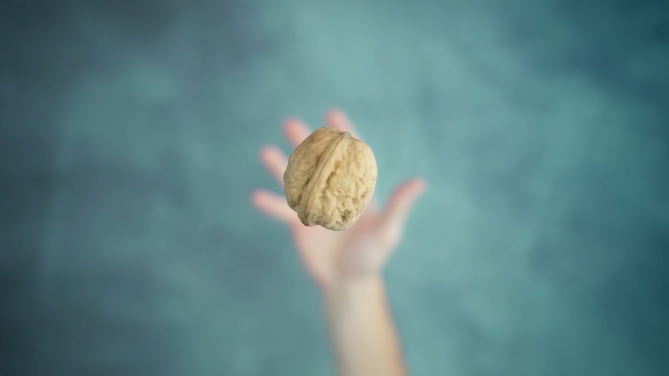 Magia delle Noci: La Noce Lanciata e Catturata dalla Mano in Slow Motion su un Tavolo Verde Macchiato