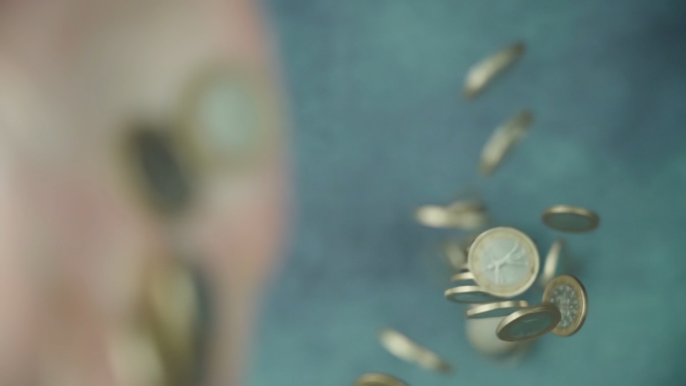 Throwing away pile of crumbling coins on green table surface