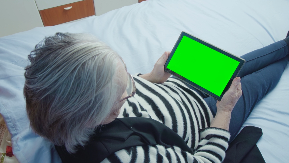 Elderly Woman Using a Tablet with Green Screen for Chroma Key