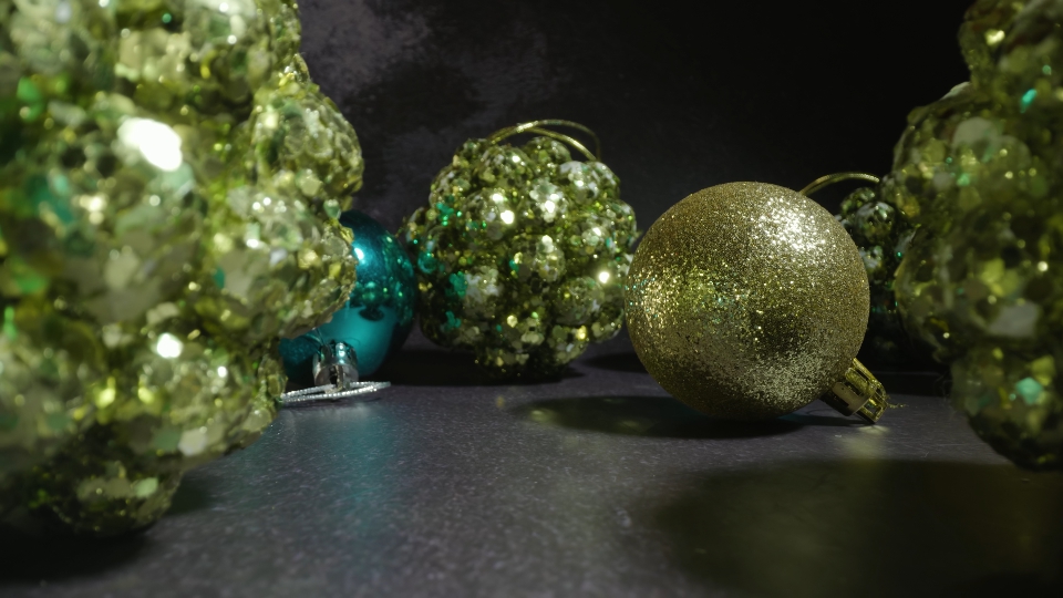 Green Christmas tree baubles with glitter on dark table