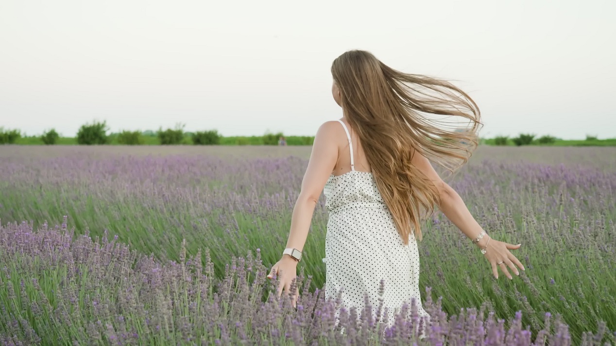 Bella giovane donna corre sul campo di lavanda verde